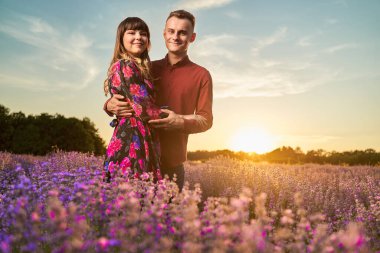 Gün batımında lavanta tarlasında harika vakit geçiren genç bir çift.