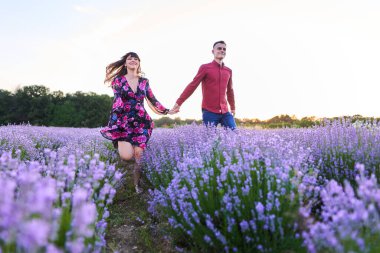 Gün batımında lavanta tarlasında harika vakit geçiren genç bir çift.