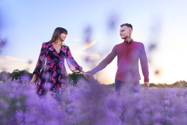 Lovely young couple having a great time in a lavender field at sunset