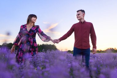 Gün batımında lavanta tarlasında harika vakit geçiren genç bir çift.