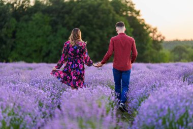 Gün batımında lavanta tarlasında harika vakit geçiren genç bir çift.