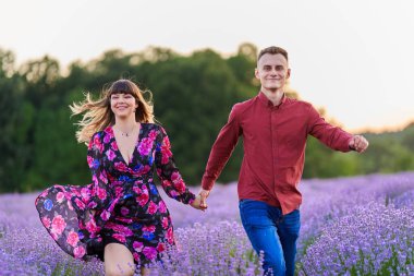 Gün batımında lavanta tarlasında harika vakit geçiren genç bir çift.
