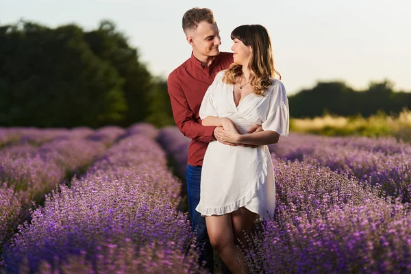 Gün batımında lavanta tarlasında harika vakit geçiren genç bir çift.