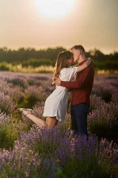 美丽的年轻夫妇在夕阳西下的薰衣草地里玩得很开心 — 图库照片