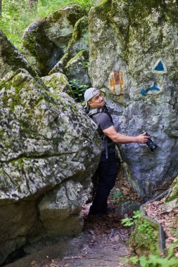 Nature photographer with camera hiking with his backpack on a trail in the mountain forest
