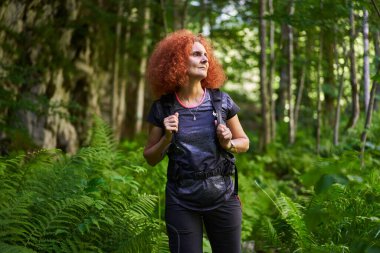 Woman hiker with backpack hiking on a trail in the mountain forest