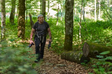 Nature photographer with camera hiking with his backpack on a trail in the mountain forest