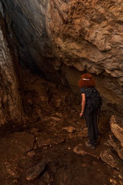 Woman with headtorch exploring a very old cave with beautiful speleothems
