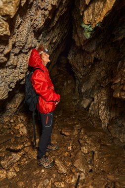 Woman with headtorch exploring a very old cave with beautiful speleothems