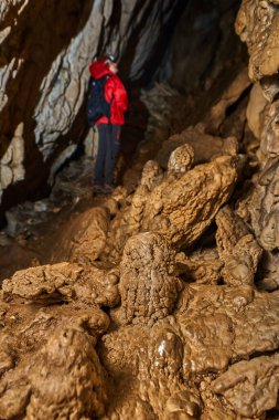 Woman with headtorch exploring a very old cave with beautiful speleothems