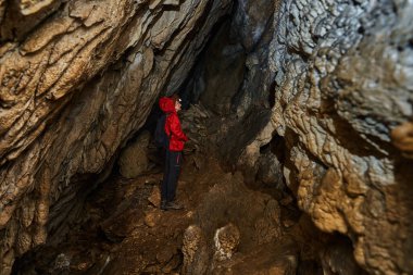 Woman with headtorch exploring a very old cave with beautiful speleothems