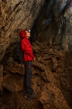 Woman with headtorch exploring a very old cave with beautiful speleothems