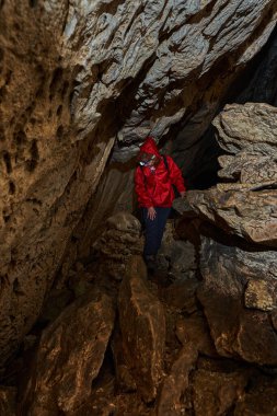Woman with headtorch exploring a very old cave with beautiful speleothems