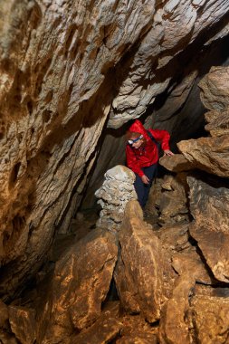 Woman with headtorch exploring a very old cave with beautiful speleothems