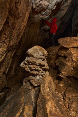 Woman with headtorch exploring a very old cave with beautiful speleothems