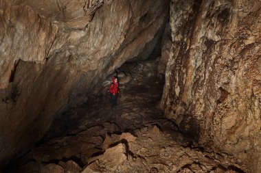 Woman with headtorch exploring a very old cave with beautiful speleothems
