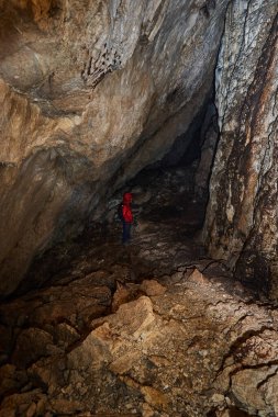 Woman with headtorch exploring a very old cave with beautiful speleothems
