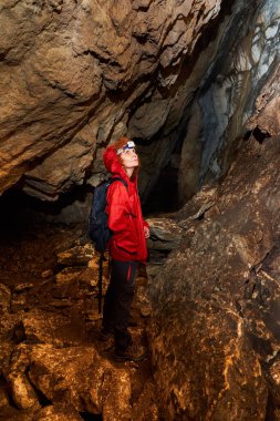 Woman with headtorch exploring a very old cave with beautiful speleothems