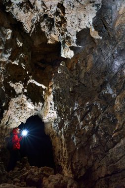 Woman with headtorch exploring a very old cave with beautiful speleothems