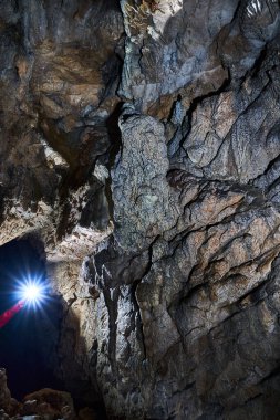 Woman with headtorch exploring a very old cave with beautiful speleothems