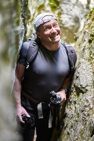 Nature photographer with camera hiking with his backpack on a trail in the mountain forest