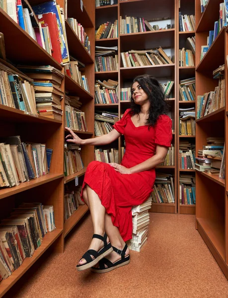 Красива Жінка Червоній Сукні Бібліотеці Сидить Стопі Книг Читаючи — стокове фото