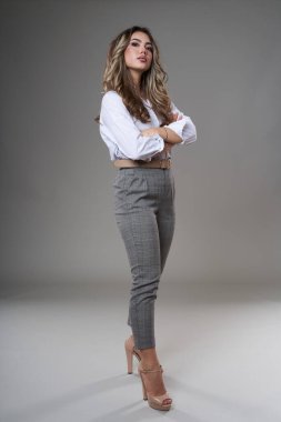 Gri arka planda çok çekici genç bir iş kadınının tam boy portresi.