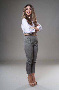 Gri arka planda çok çekici genç bir iş kadınının tam boy portresi.