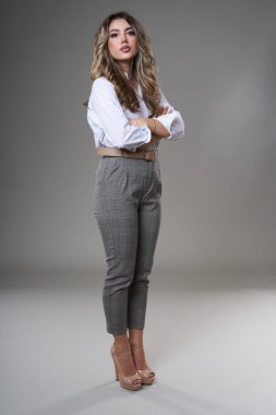 Gri arka planda çok çekici genç bir iş kadınının tam boy portresi.