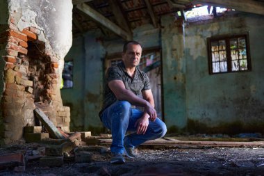 Harabe bir ev ve ahırda orta yaşlı bir adam, doğal ışık portresi