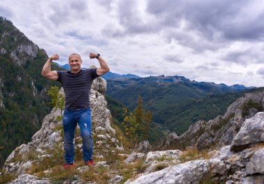 Kayalık dağların tepesindeki atletik adam