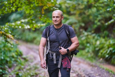 Profesyonel doğa fotoğrafçısı dağ ormanlarında kamera ve sırt çantasıyla yürüyüş yapıyor.