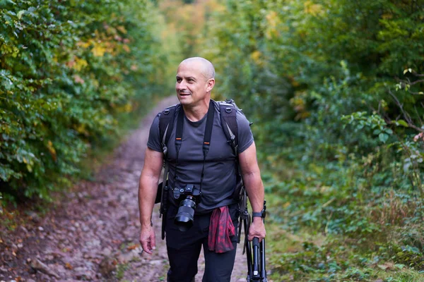 전문적 사진사가 카메라와 가방을 숲에서 하이킹을 — 스톡 사진