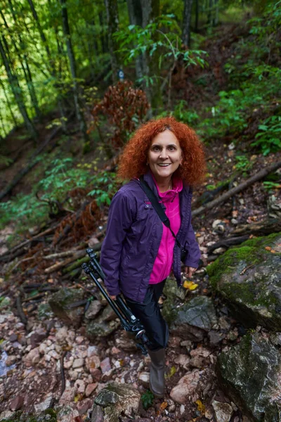 山の森の中の歩道で巻き毛やカメラのハイキングと赤毛の女性 — ストック写真