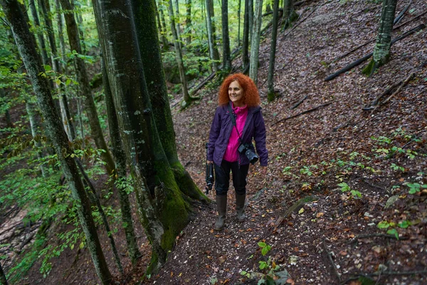 Kıvırcık Saçlı Kameralı Kızıl Saçlı Bir Kadın Dağ Ormanında Yürüyüş — Stok fotoğraf