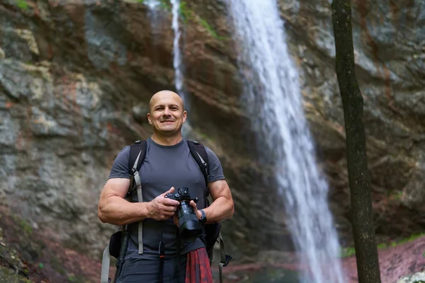 Dağ Ormanında Şelalenin Yanında Kamera Sırt Çantasıyla Profesyonel Doğa Fotoğrafçısı — Stok fotoğraf