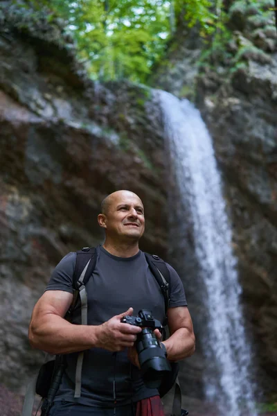 Dağ Ormanında Şelalenin Yanında Kamera Sırt Çantasıyla Profesyonel Doğa Fotoğrafçısı — Stok fotoğraf