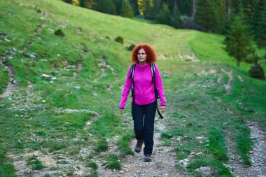 Vahşi ormanda yürüyüş yapan kıvırcık saçlı kadın.