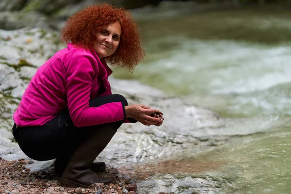 Žena Turista Kudrnaté Červené Vlasy Sbírat Barevné Oblázky Břehu Řeky — Stock fotografie