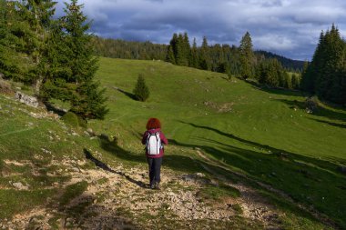Sırt çantalı bir kadın dağda yürüyüş yapıyor.