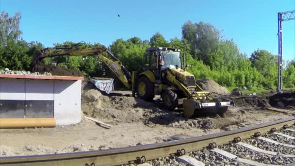 Excavadora cava un agujero cerca de las vías del ferrocarril — Vídeos de Stock