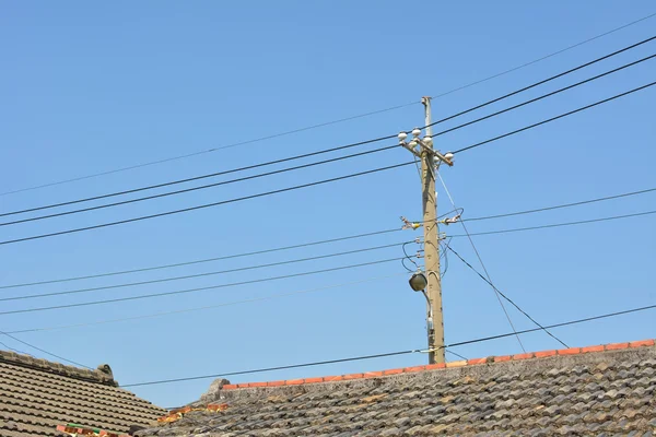 Pólo de energia perto do telhado — Fotografia de Stock