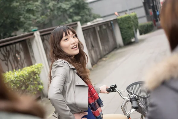 Joven mujer asiática montando bicicleta con amigos — Foto de Stock