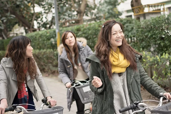 Joven mujer asiática montando bicicleta con amigos —  Fotos de Stock