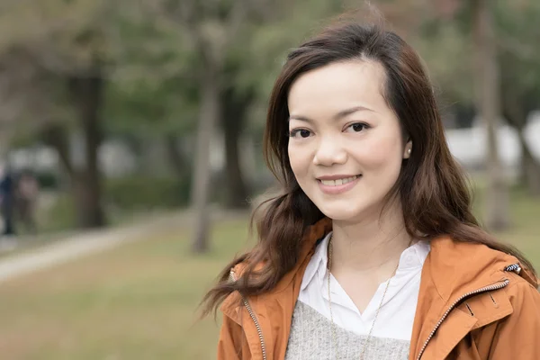 Счастливая улыбающаяся азиатская молодая женщина в парке — стоковое фото