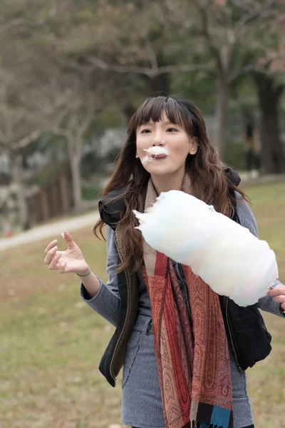 Young Asian woman eating cotton candy — Stock Photo, Image