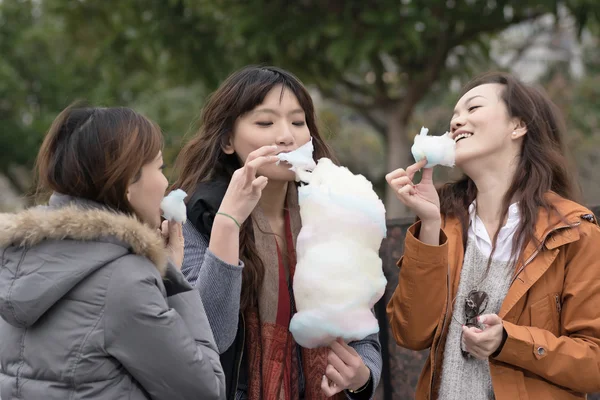 Šťastné mladé asijské ženy jíst cotton candy se svými přáteli — Stock fotografie