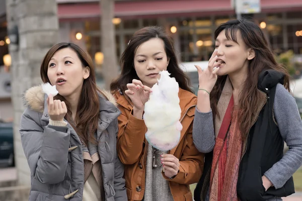 Feliz joven asiática comiendo algodón de azúcar con sus amigos — Foto de Stock