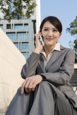 cep telefonu kullanarak Asya iş kadını gülümseyen ve merdivenlerde otur bir