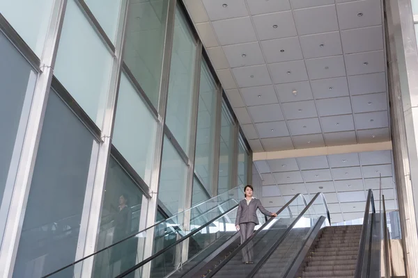 Mujer de negocios asiática parada en escalera mecánica — Foto de Stock